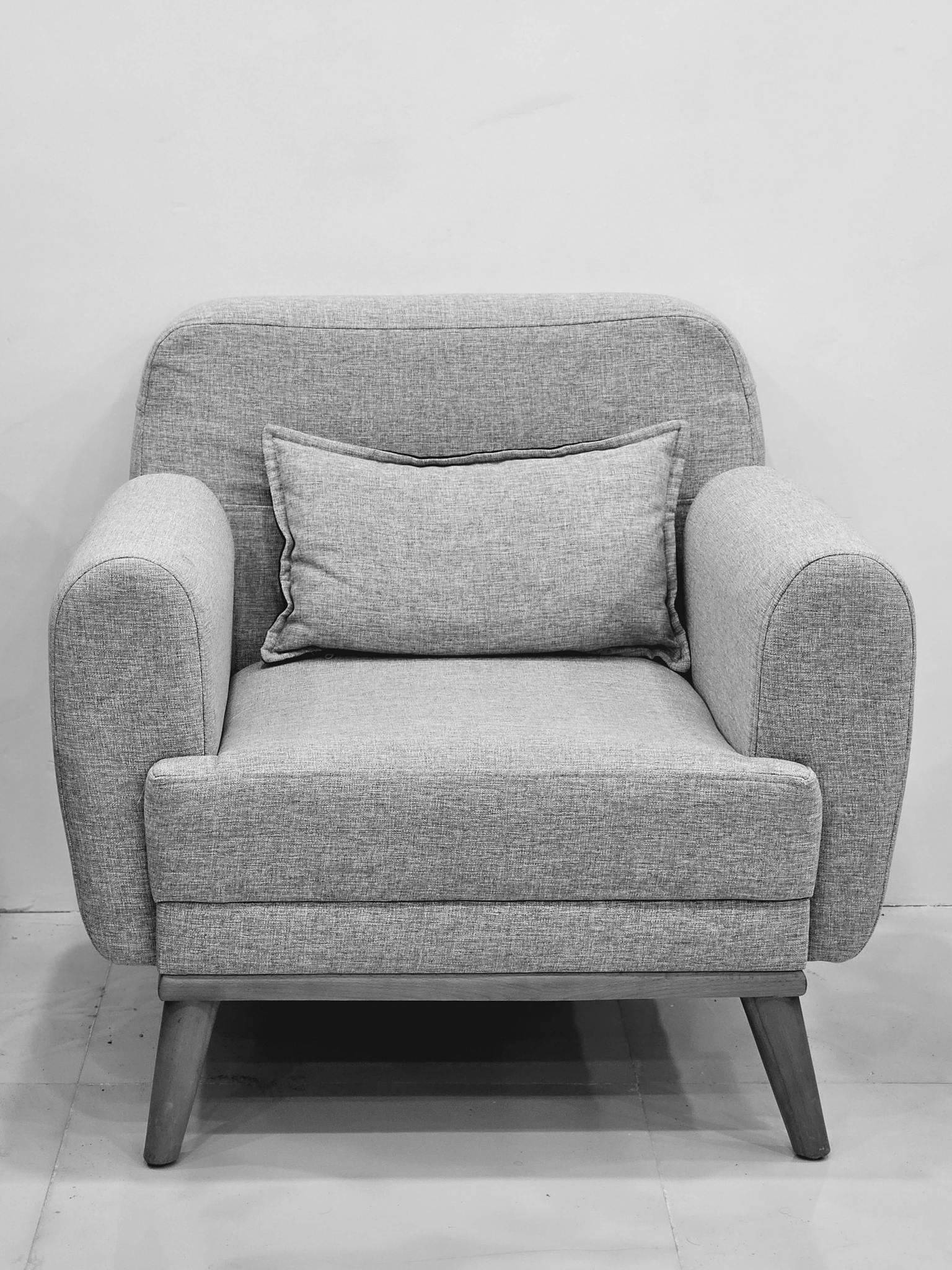 Elegant black and white photo of a modern armchair with a cushion.